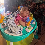 Chloe is registered to the contest to win money with this photo: baby, baby_walker, blanket, child, couch, cozy, face, floor, floor_tile, furniture, hair, home, indoor, person, pink_clothing, playful, resting, sleeping, toddler, toy