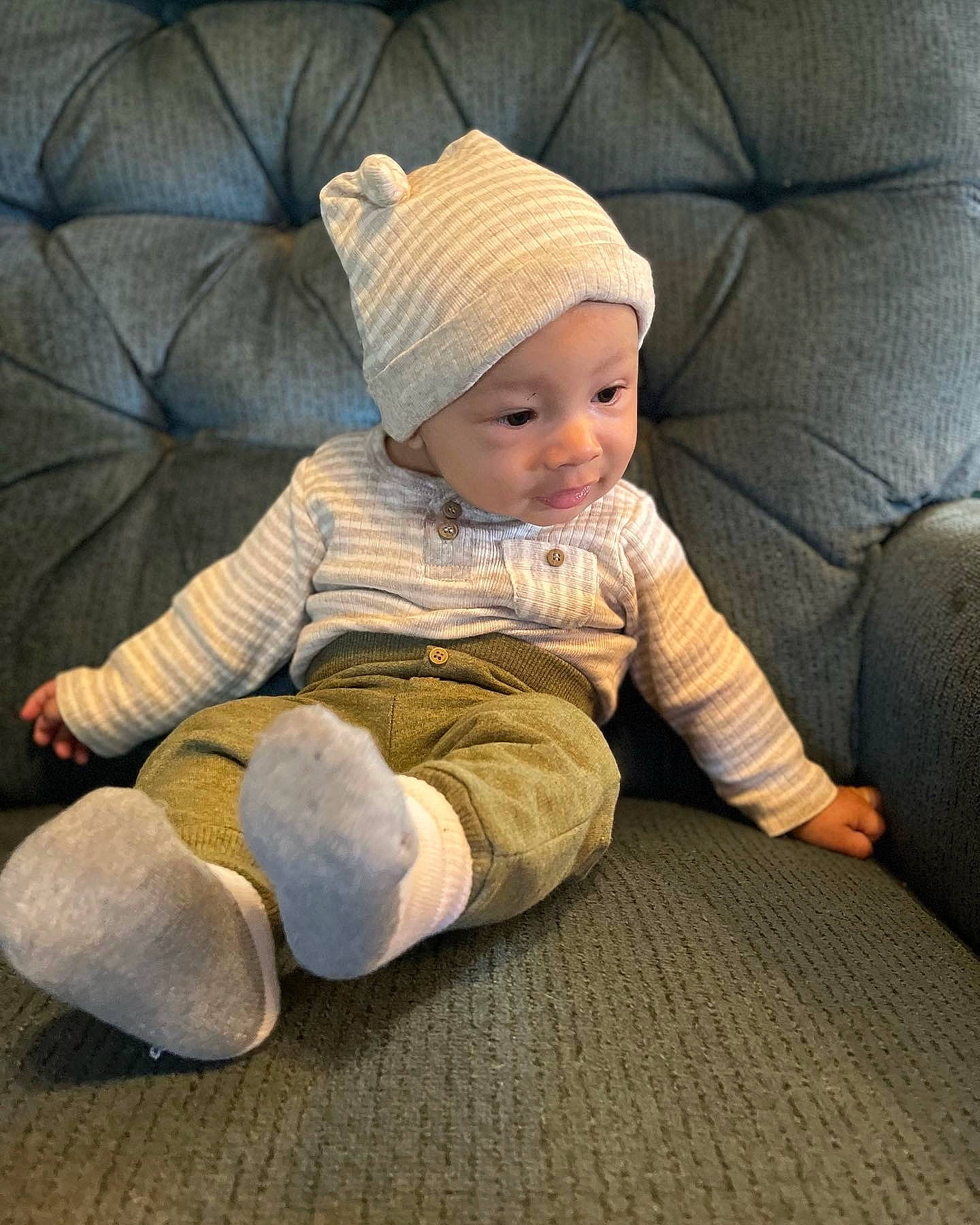 Josiah joined the competition — help win amazing prizes! baby, baby_toddler_clothing, beanie, cap, child, comfort, couch, fashion_accessory, flooring, foot, headwear, human_leg, knit_cap, lap, person, room, sitting, sleeve, smile, toddler