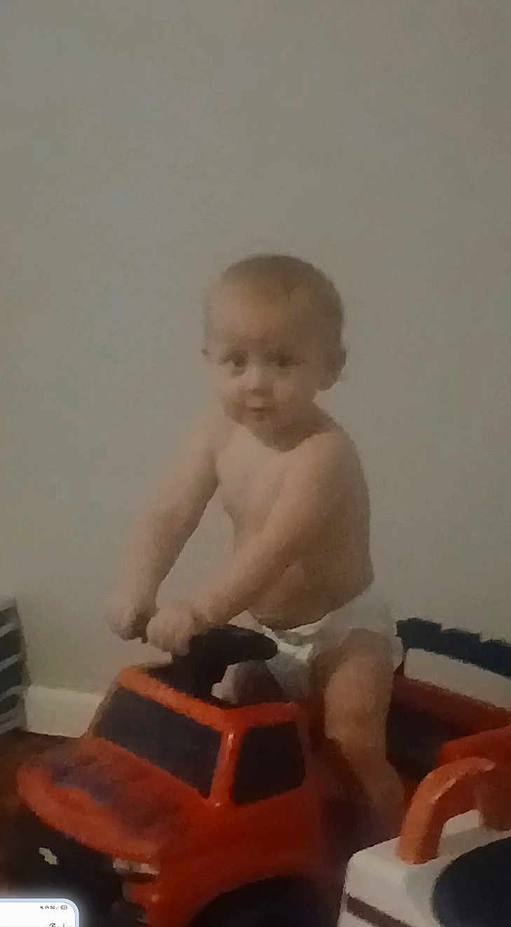 Creed joined the competition — help win amazing prizes! toddler, child, toy_truck, diaper, indoor, baby, play, vehicle, steering_wheel, floor, curious, blurry, young_child, person, plastic_toy, hands, face, head, sitting, room