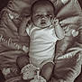 baby, infant, blanket, onesie, crocheted_booties, heart_pattern, lying_down, curious_expression, soft_texture, cozy, monochrome, portrait, cute, newborn, hands, feet, fabric, sleepwear, resting, indoor