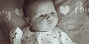 Audrey joined the competition — help win amazing prizes! baby, infant, face, onesie, heart_pattern, blanket, soft_texture, expression, lying_down, portrait, cute, newborn, sleepwear, cozy, indoor, skin, head, hand, child, monochrome