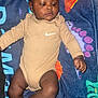 Damani is registered to the contest to win money with this photo: baby, child, infant, onesie, beige_clothing, blanket, dinosaur_pattern, colorful, lying_down, cute, indoor, person, skin, face, hand, foot, soft_texture, calm_expression, young_child, casual