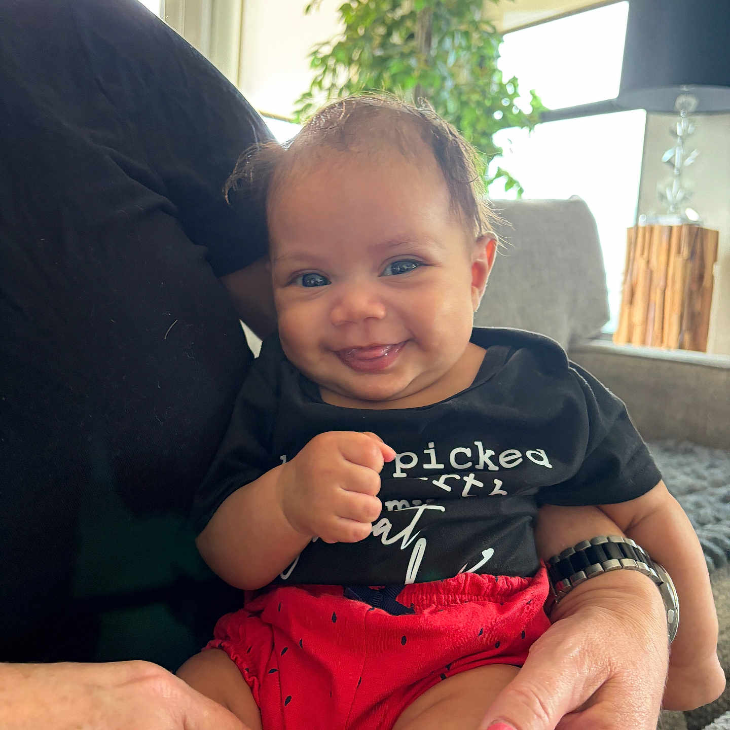 Alaia joined the competition — help win amazing prizes! adult_hand, baby, black_shirt, cozy, cute, happy, indoor, infant, lamp, laughing, living_room, nail_polish, person, plant, portrait, red_shorts, smile, sofa, watch, window