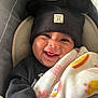 baby, smiling, blanket, hat, black_clothing, car_seat, face, child, cute, cozy, indoor, infant, headwear, happy, person, portrait, warm, childcare, closeup, comfort
