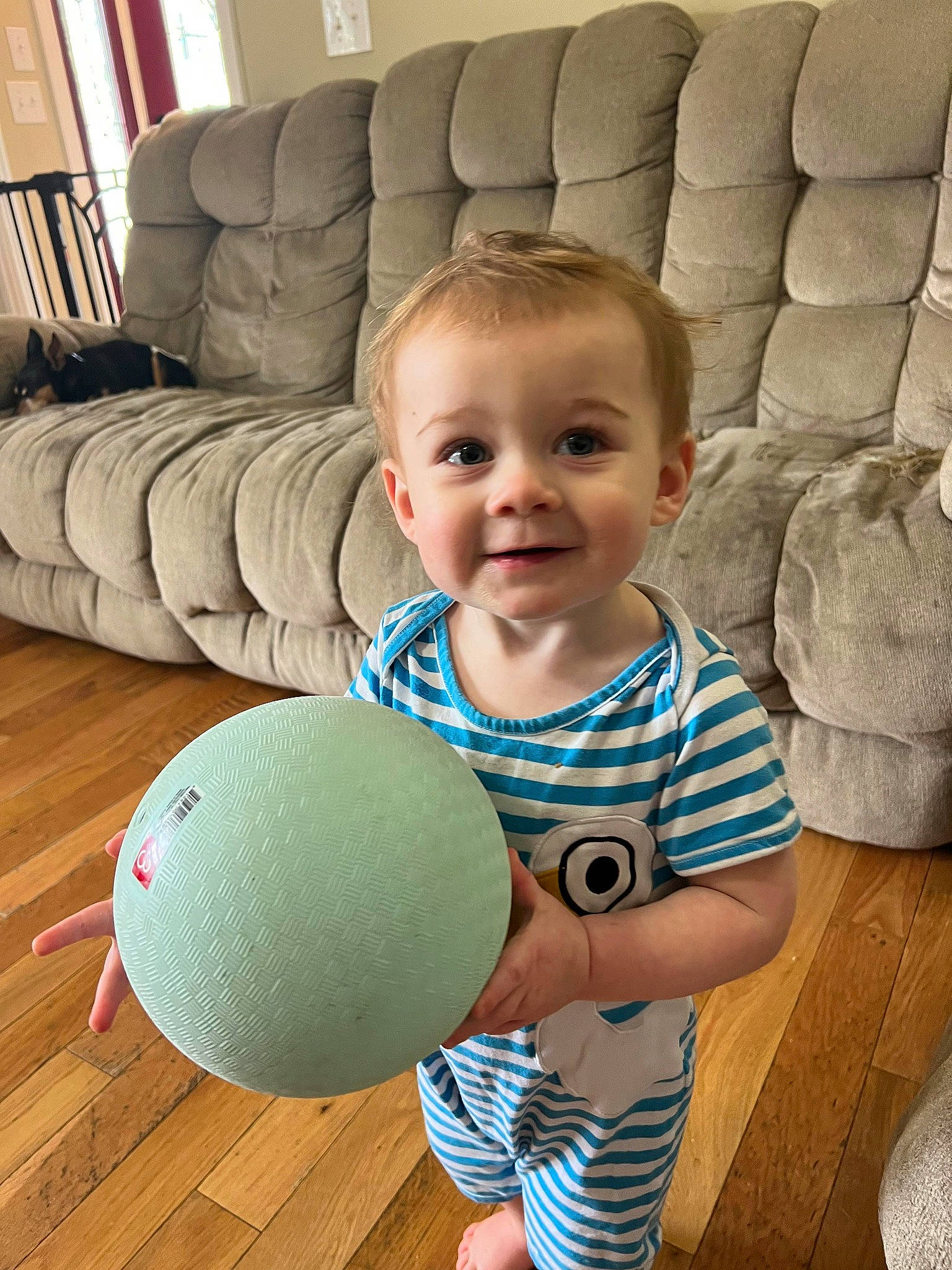 Elliot is registered to the contest to win money with this photo: baby, baby_toddler_clothing, ball, chair, cheek, comfort, eye, face, floor, flooring, furniture, hairstyle, happy, joy, organ, person, skin, smile, standing, t_shirt