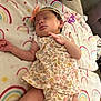 baby, newborn, sleeping, floral_outfit, headband, bow, blanket, rainbow_pattern, infant, cute, resting, soft_texture, peaceful, child, indoors, fabric, clothing, hand, leg, face