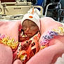 newborn, baby, pink_blanket, crocheted_edges, white_hat, hospital_bed, indoor, person, adult, seated, standing, blanket, bed, medical, resting, peaceful, wrapped, infant, clothing, closeup