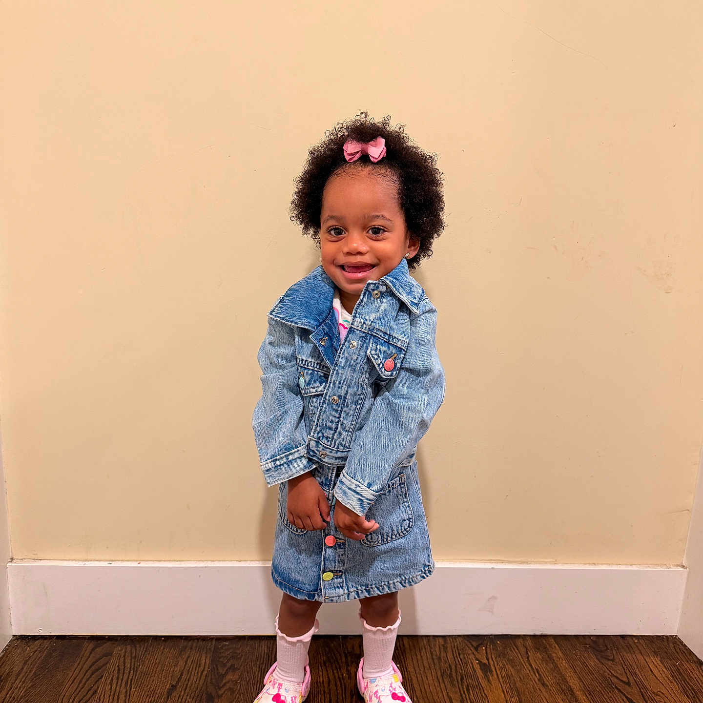 Trinity joined the competition — help win amazing prizes! child, toddler, girl, portrait, smiling, standing, denim, jacket, skirt, pink_bow, curly_hair, dark_skin, socks, shoes, fashion, indoors, wall, wooden_floor, full_body, happy