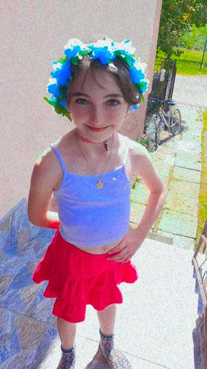 Natalia joined the competition — help win amazing prizes! child, girl, flower_crown, tank_top, red_skirt, outdoor, smiling, standing, bicycle, sidewalk, sunlight, necklace, choker, happy, person, footwear, socks, summer, fashion, portrait