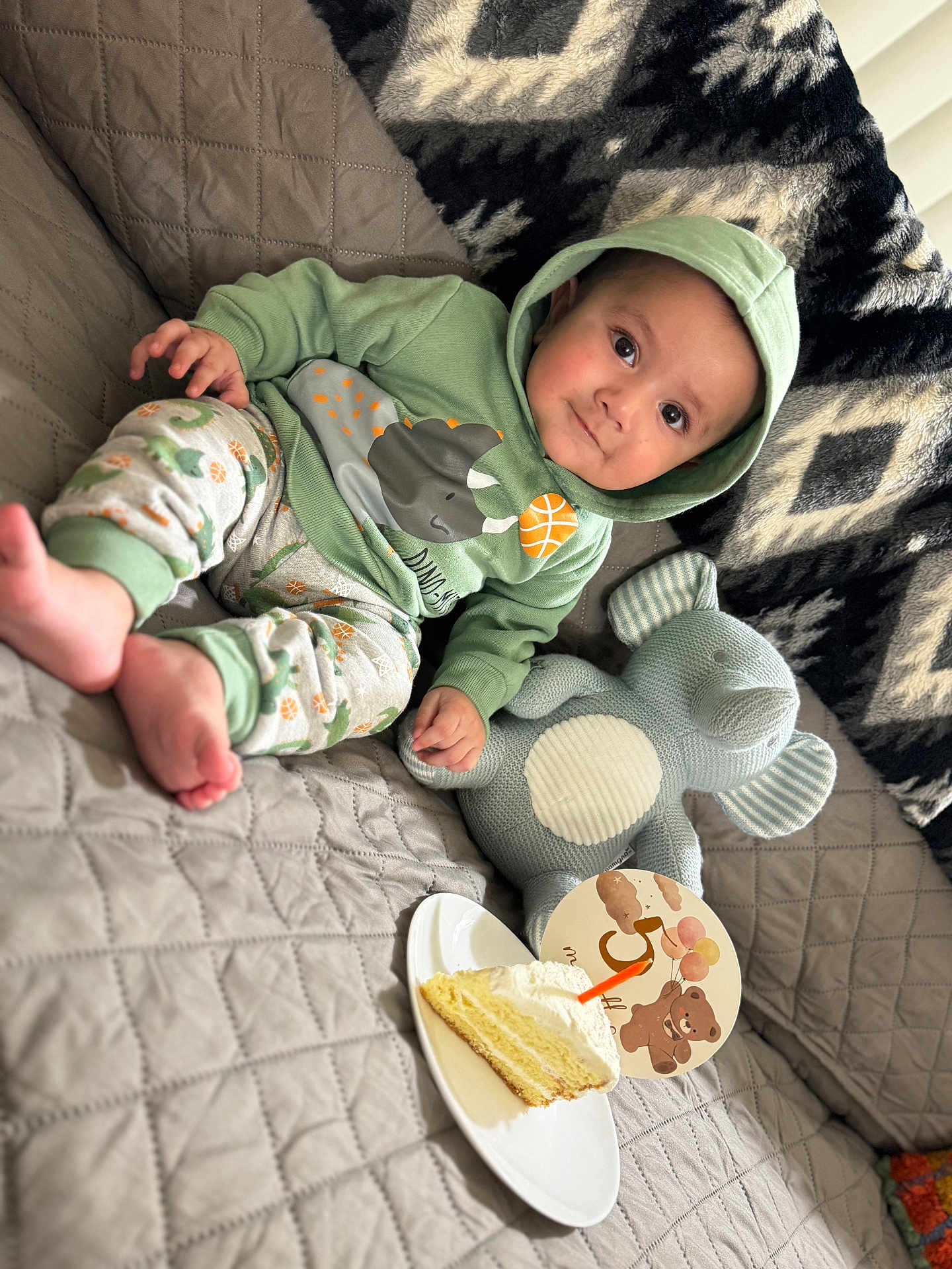 Mustafa joined the competition — help win amazing prizes! baby, infant, child, hoodie, pajamas, stuffed_animal, elephant_toy, cake, slice_of_cake, plate, sofa, blanket, quilt, smile, portrait, indoor, cozy, celebration, cute, happy
