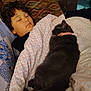 August joined the competition — help win amazing prizes! child, sleeping, cat, gray_cat, blanket, couch, curly_hair, patterned_fabric, indoor, cozy, relaxation, pet, pink_collar, nap, comfort, young, resting, animal, closeup, soft_lighting