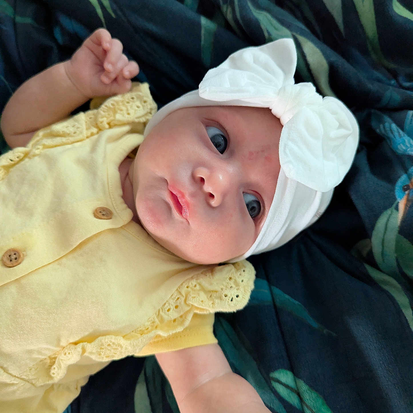 Inayah joined the competition — help win amazing prizes! arm, baby, blanket, child, cute, expression, eyes, fabric, face, hand, headband, infant, laying_down, newborn, pattern, portrait, skin, soft_lighting, white_bow, yellow_clothing