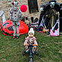 Hailey is registered to the contest to win money with this photo: toddler, child, tricycle, grass, halloween, costume, clown, balloon, skeleton, ghost, scary, decoration, outdoor, hat, pink, orange, black, green, face, toy