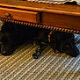 dog, black_dog, wooden_table, carpet, indoor, pets, hiding, resting, collar, floor, animal, two_dogs, furniture, cozy, home, texture, quiet, companions, relaxing, shadow