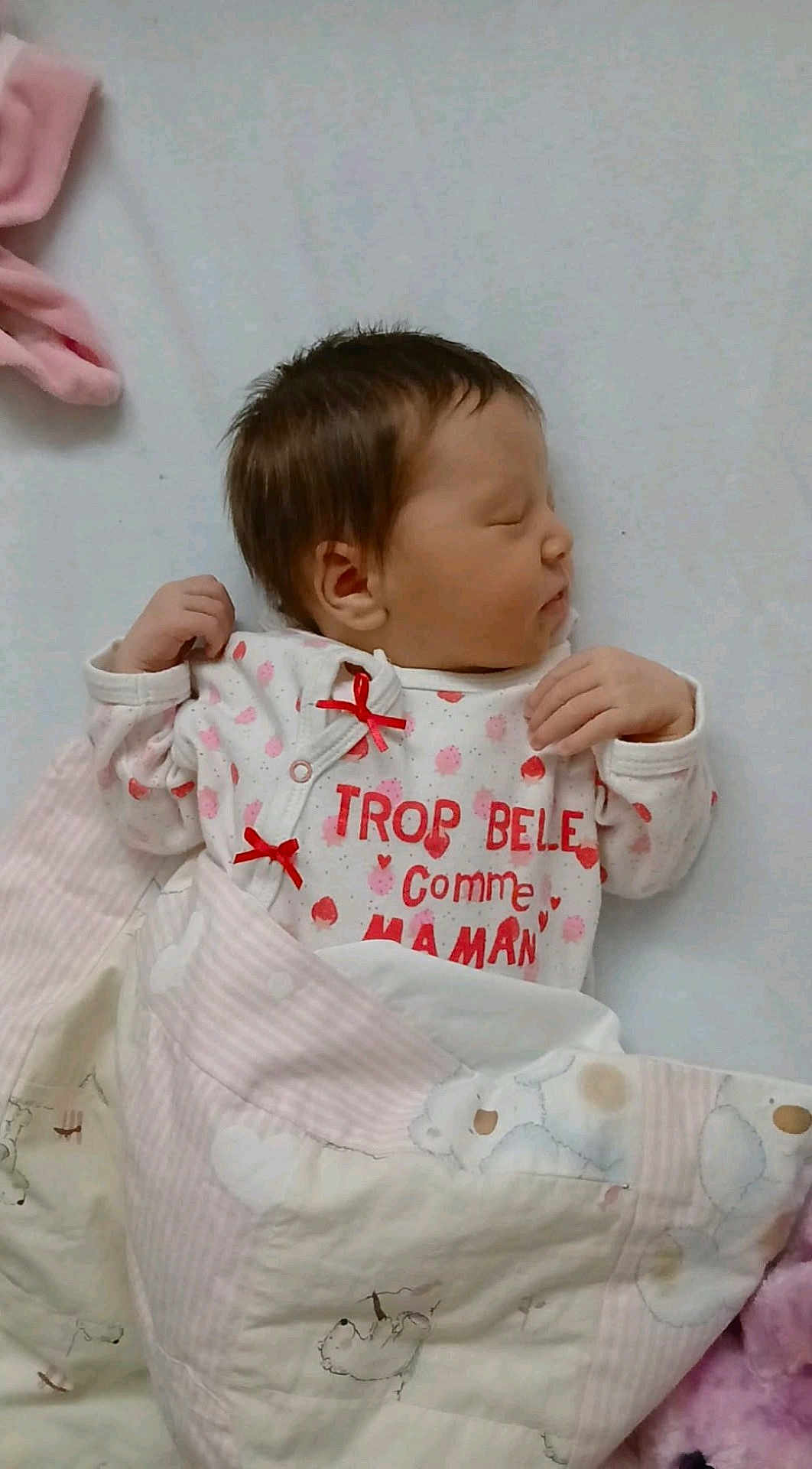 Alyia a rejoint le concours — aidez-le/la à gagner de superbes lots ! newborn, baby, sleeping, blanket, quilt, infant, clothing, red_bow, text, face, hand, bed, soft, pastel, pink, white, peaceful, cute, portrait, indoors
