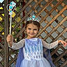 Sofi is registered to the contest to win money with this photo: child, girl, princess, costume, dress, tiara, wand, smile, blue, outdoor, lattice, wood, cape, magic, happy, portrait, person, fairy_tale, cute, playful