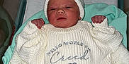 Creed is registered to the contest to win money with this photo: newborn, baby, hospital, bassinet, blanket, knitted_clothing, hat, infant, hospital_id_band, lying_down, white_clothing, plush_blanket, wooden_sign, name_tag, cute, indoors, resting, small_hands, soft_lighting, peaceful