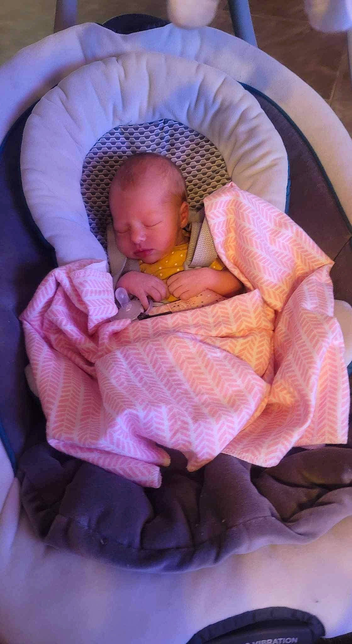 Chloe is registered to the contest to win money with this photo: baby, baby_carriage, baby_products, baby_safety, baby_sleeping, baby_toddler_clothing, bedtime, cheek, comfort, eye, hand, human_body, infant_bed, lap, linens, nap, person, pink, sitting, textile