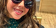 Alyssa participe au concours pour gagner de l'argent avec cette photo : child, girl, smiling, sunglasses, long_hair, curly_hair, indoor, wooden_floor, jacket, green_shirt, polka_dots, eyeglasses, display, retail_store, happy, portrait, casual, fashion, person, cute