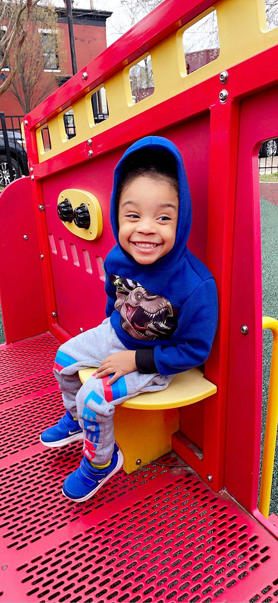 Mario is registered to the contest to win money with this photo: baby_toddler_clothing, child, city, electric_blue, flooring, fun, happy, joy, leisure, magenta, orange, outdoor_play_equipment, person, play, playground, recreation, red, smile, snapshot, standing