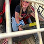 casual_clothing, child, dashboard, girl, grip, hand, happy, long_hair, metal_bars, outdoor, playful, rust, scrunchie, seat, seatbelt, smile, steering_wheel, sunglasses, sunlight, vehicle