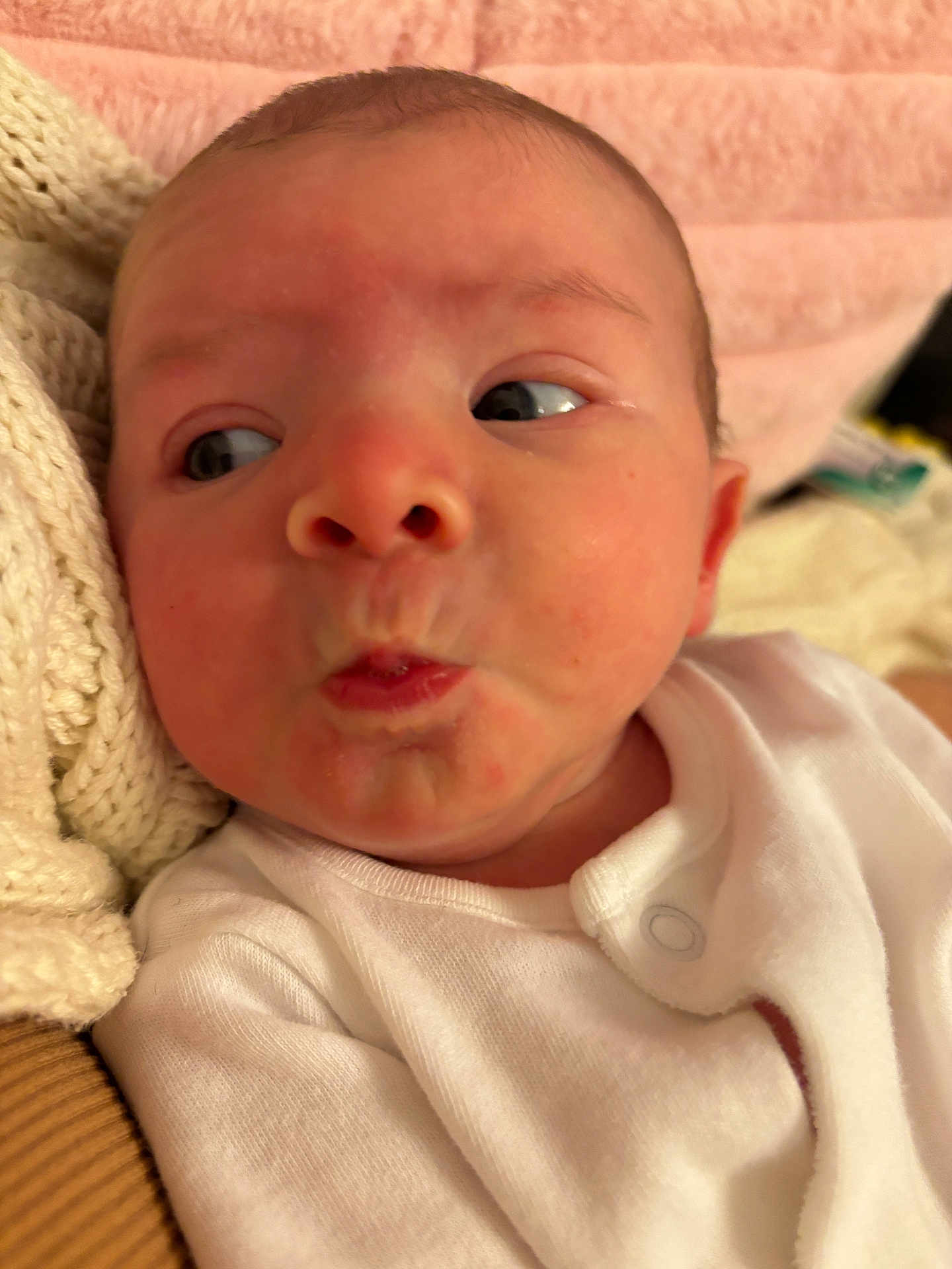 Frankie joined the competition — help win amazing prizes! baby, infant, face, expression, pursed_lips, clothing, white_outfit, knitwear, closeup, skin, newborn, person, cute, head, eyes, indoors, soft_texture, blanket, cozy, portrait
