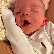 Frankie joined the competition — help win amazing prizes! baby, infant, sleepy, close_up, face, white_clothing, blanket, soft_texture, pink_background, newborn, cute, resting, peaceful, skin, mouth_open, hand, knitted_blanket, portrait, indoors, warm