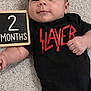 Levi is registered to the contest to win money with this photo: baby, infant, carpet, black_onesie, slayer, chalkboard, 2_months, child, cute, lying_down, hand, face, smiling, indoor, soft_texture, clothing, portrait, young, skin, expression