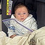 baby, infant, car_seat, blanket, keys, plastic_bag, white_clothing, indoor, face, person, child, young, blue_eyes, curly_hair, soft_texture, comfort, seat, closeup, expression, wrapped