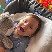 Lorenzo a rejoint le concours — aidez-le/la à gagner de superbes lots ! baby, child, smiling, stuffed_animal, toy, blue_clothing, blanket, seat, indoor, happy, face, infant, cuddling, plush_toy, home, colorful, soft, cozy, radiator, wood_floor