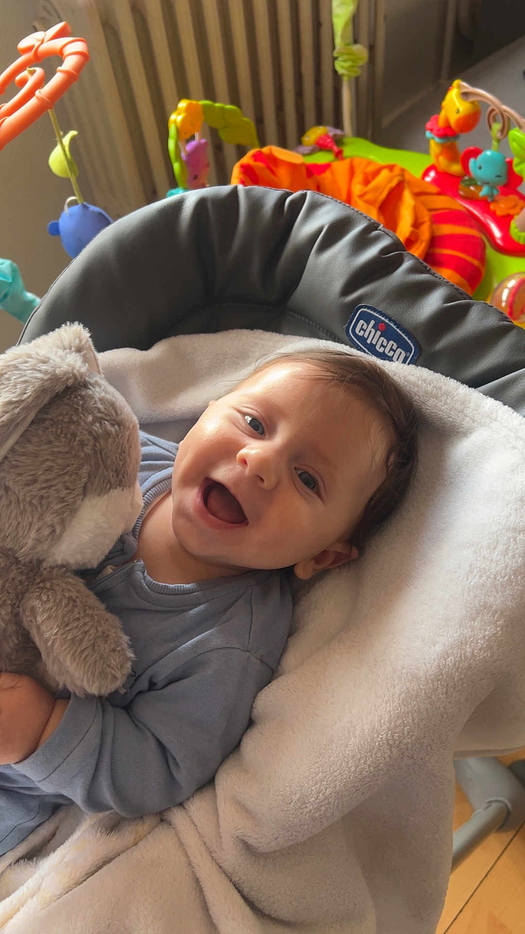 Lorenzo a rejoint le concours — aidez-le/la à gagner de superbes lots ! baby, child, smiling, stuffed_animal, toy, blue_clothing, blanket, seat, indoor, happy, face, infant, cuddling, plush_toy, home, colorful, soft, cozy, radiator, wood_floor