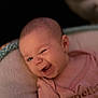 baby, infant, winking, cute, smiling, pink_shirt, face, head, person, child, cushion, soft, seat, portrait, expression, closeup, happy, indoors, newborn, human