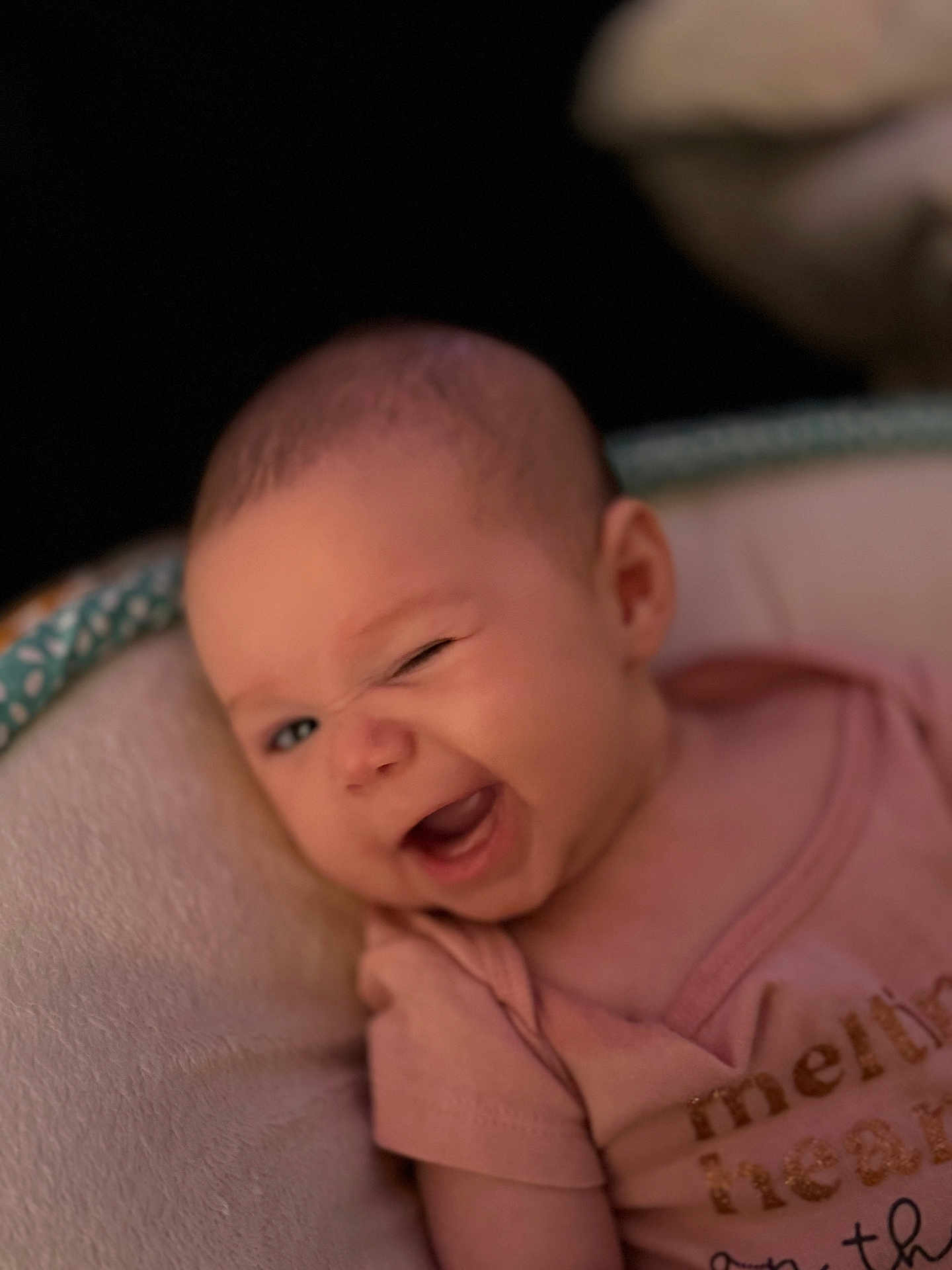 Lucy is registered to the contest to win money with this photo: baby, infant, winking, cute, smiling, pink_shirt, face, head, person, child, cushion, soft, seat, portrait, expression, closeup, happy, indoors, newborn, human