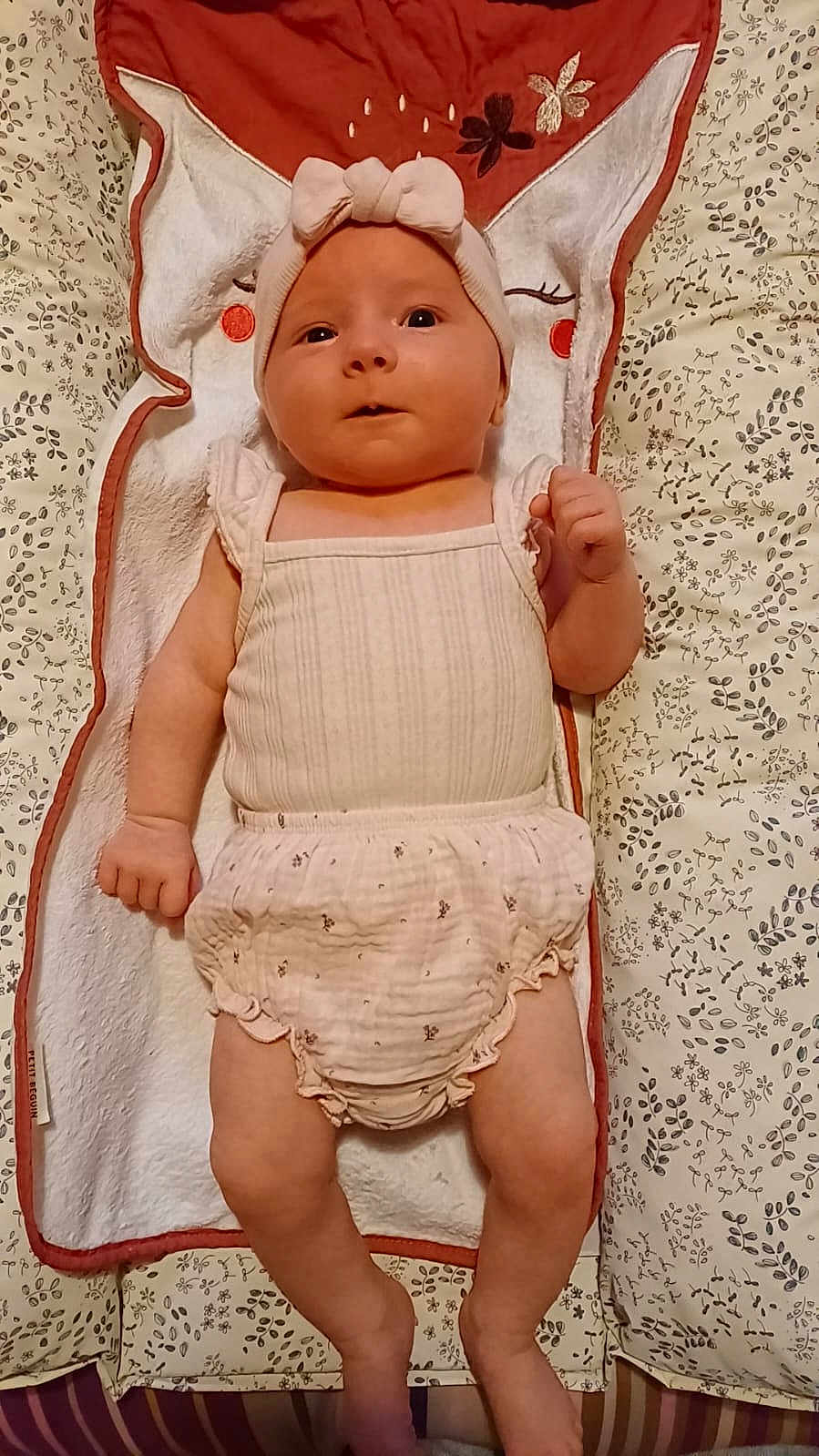 Thaïs a rejoint le concours — aidez-le/la à gagner de superbes lots ! baby, infant, headband, romper, blanket, patterned, towel, fox_design, cute, lying_down, indoors, soft_fabric, curious, wide_eyes, small_hands, child, adorable, sleeping_area, cozy, pink