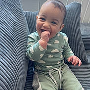 Owen participe au concours pour gagner de l'argent avec cette photo : baby, child, clothing, couch, cozy, cute, face, furniture, hand_in_mouth, happy, indoor, infant, pajamas, person, pillow, relaxed, sitting, smiling, window, young_child