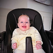 Novella joined the competition — help win amazing prizes! baby, child, high_chair, smiling, happy, indoor, cozy_clothing, face, person, infant, seated, cute, light_skin, buttoned_sweater, furniture, home, portrait, young_child, expression, comfort