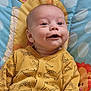 Kobie is registered to the contest to win money with this photo: baby, infant, smile, yellow_onesie, dinosaur_pattern, play_mat, colorful, happy, child, face, cute, lying_down, indoors, young_child, apparel, head, eyes, joyful, soft_texture, comfortable