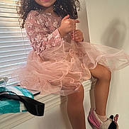 Pietra is registered to the contest to win money with this photo: child, girl, smile, curly_hair, pink_dress, sitting, window, blinds, natural_light, slippers, minnie_mouse, happy, indoor, legs, playful, cute, cozy, home, fashion, portrait