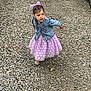 child, toddler, girl, purple_dress, denim_jacket, bow, hair_accessory, walking, gravel, outdoor, curious, polka_dots, footwear, expression, casual_clothing, daylight, nature, small_person, cute, playful