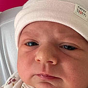 Justine participe au concours pour gagner de l'argent avec cette photo : baby, newborn, hat, face, closeup, expression, clothing, pink, white, red_background, infant, skin, eyes, mouth, nose, soft_fabric, button, sleepwear, person, portrait