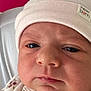 baby, newborn, hat, face, closeup, expression, clothing, pink, white, red_background, infant, skin, eyes, mouth, nose, soft_fabric, button, sleepwear, person, portrait