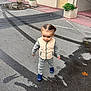 toddler, child, street, asphalt, wet, puddle, tire_marks, vest, shoes, building, planters, plants, urban, outdoor, sidewalk, curb, door, concrete, person, walking