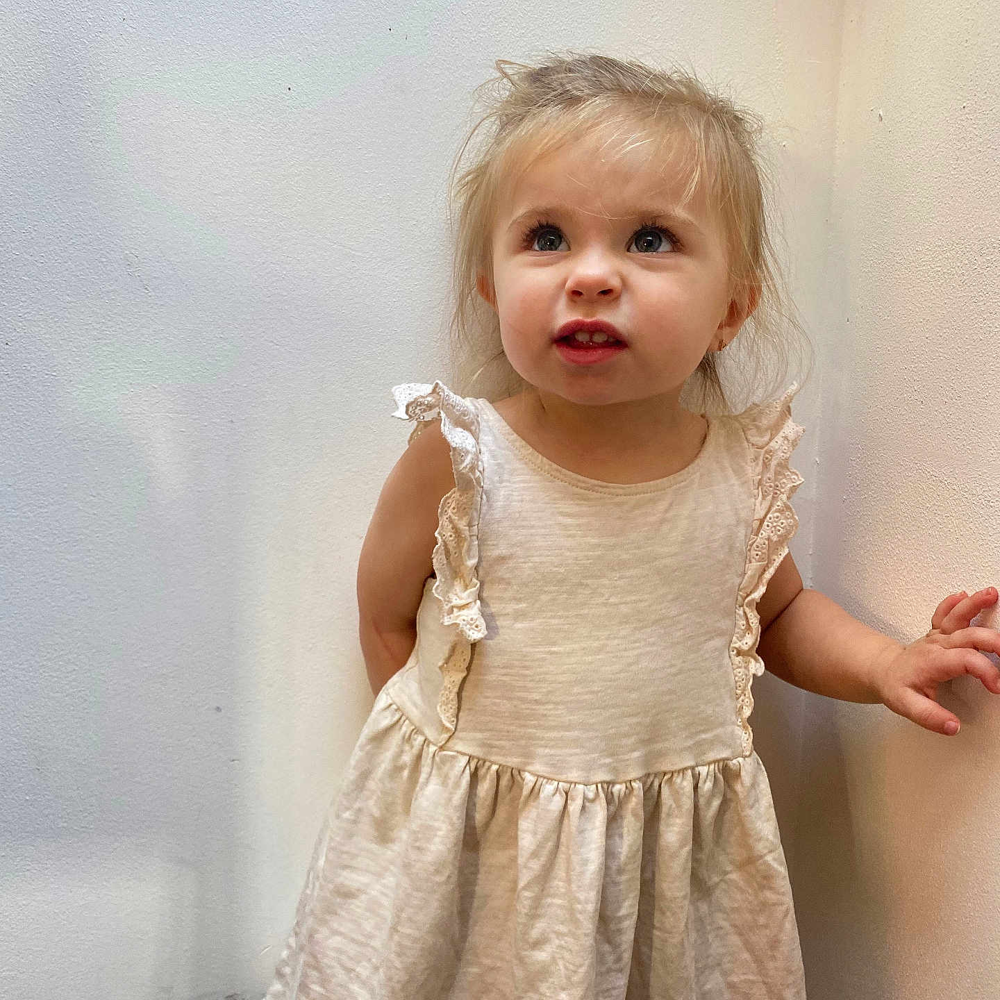 Laïss a rejoint le concours — aidez-le/la à gagner de superbes lots ! casual_clothing, child, cream_color, curly_hair, cute, dress, expression, girl, hands, indoor, innocent, light_skin, looking_up, person, portrait, small_child, standing, toddler, wall, young_child
