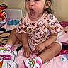 toddler, child, surprised, pink_clothing, hello_kitty, bows, bed, colorful_bedspread, shoes, rainbow, indoor, person, young_child, expression, cute, casual, sitting, hair_bow, footwear, room