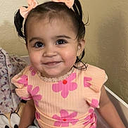Sariyah is registered to the contest to win money with this photo: toddler, child, smiling, pink_flower_shirt, denim_skirt, hair_bows, indoor, seated, happy, cute, portrait, young_girl, playful, skin, face, person, clothing, casual, home, cozy