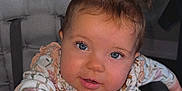 Wrenlee is registered to the contest to win money with this photo: baby, child, high_chair, cute, smiling, blue_eyes, hair_buns, hand, table, indoor, clothing, long_sleeve, face, expression, infant, portrait, person, young, seat, curious