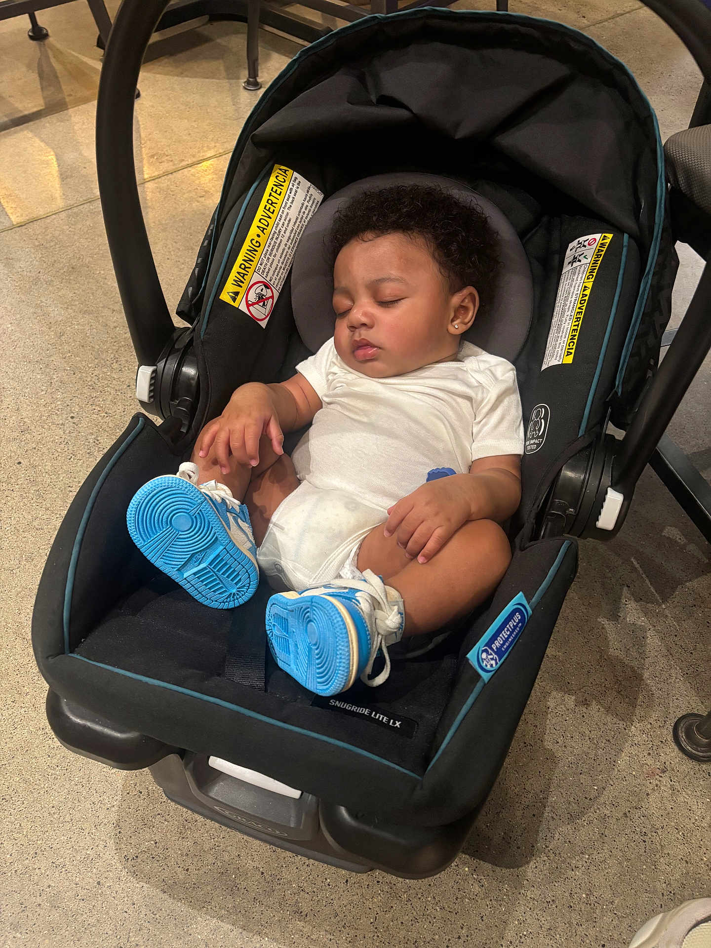 Jaylen joined the competition — help win amazing prizes! baby, infant, sleeping, car_seat, blue_sneakers, curly_hair, white_onesie, indoor, floor, footwear, child, person, seat, clothing, head, peaceful, rest, cute, small, toddler