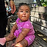Willow is registered to the contest to win money with this photo: baby, bench, casual, child, curly_hair, cute, daylight, expression, hand, nature, outdoor, person, pink_clothing, shadow, sitting, skin, sunlight, tree, water_drops, wood