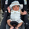 baby, car_seat, child, clothing, cute, expression, face, foot, hand, hat, infant, newborn, outdoor, overalls, person, portrait, safety, seatbelt, stripes, sun_hat