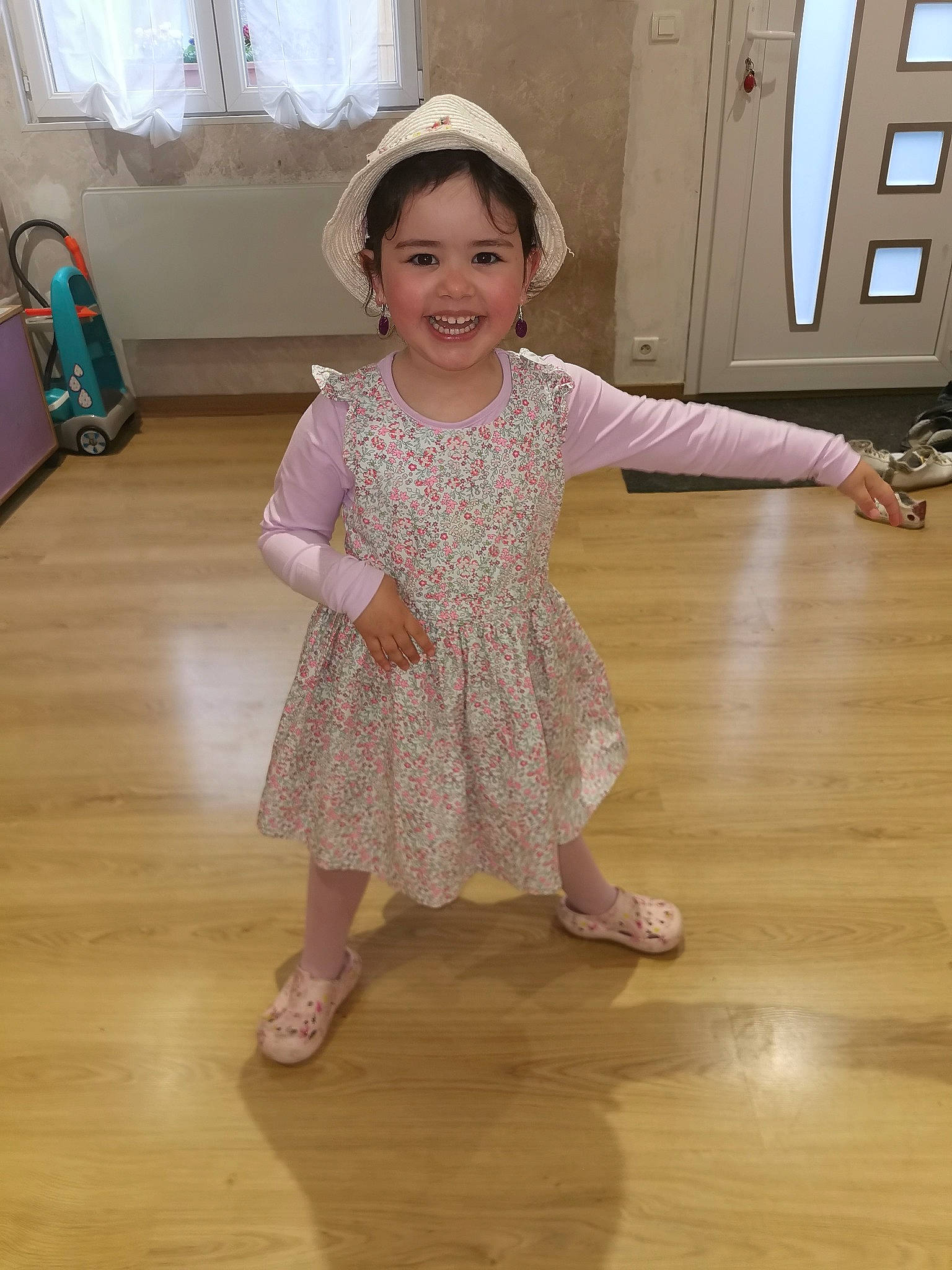 Emy participe au concours pour gagner de l'argent avec cette photo : baby_toddler_clothing, dress, floor, flooring, happy, hardwood, headwear, joint, joy, leg, neck, one_piece_garment, person, shoe, shoulder, skin, sleeve, smile, standing, toddler